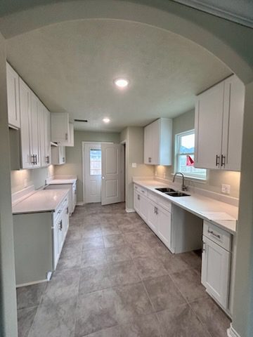 Modern kitchen with white cabinets and tiles.
