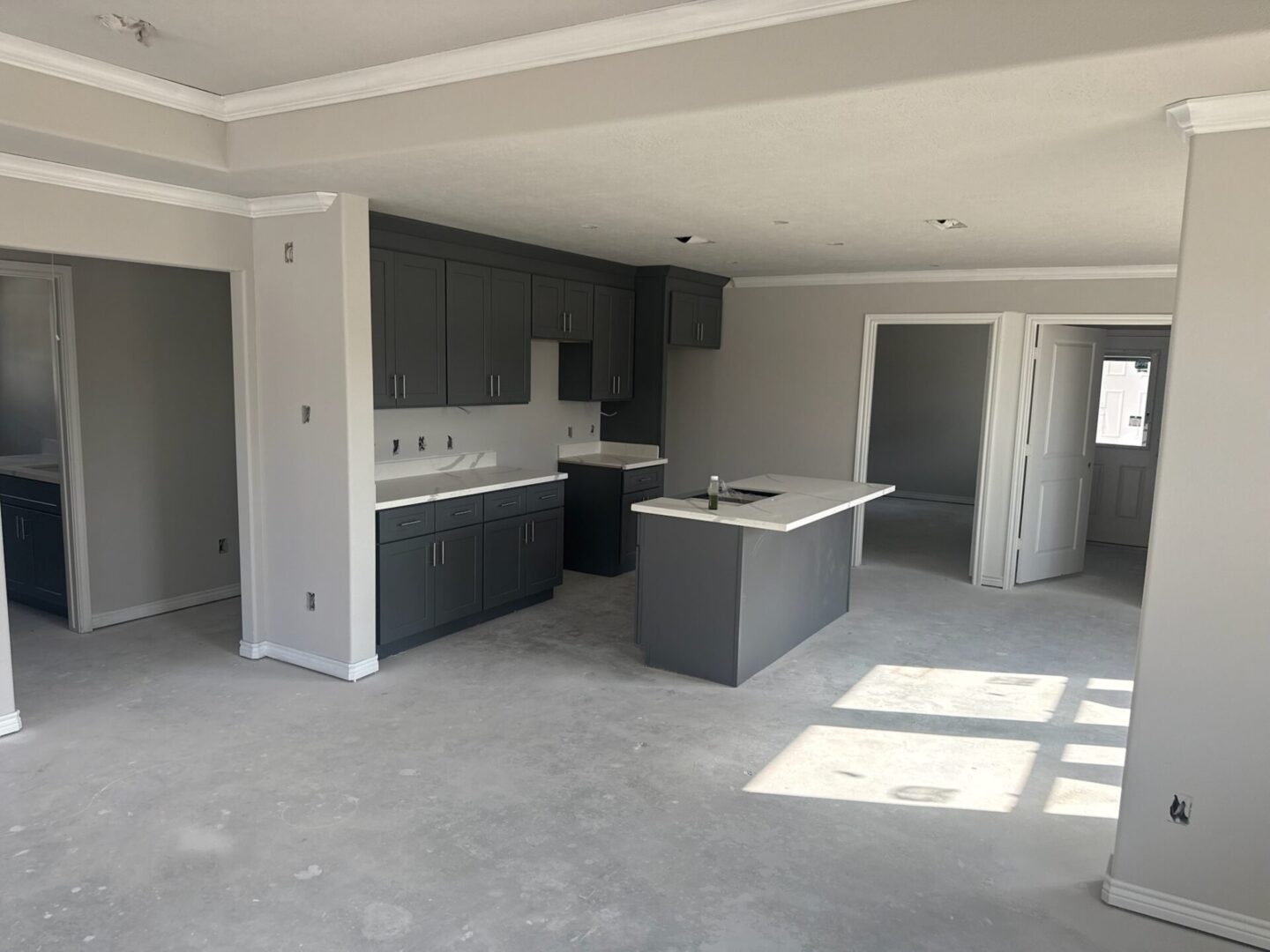 Unfinished kitchen with gray cabinets and island.