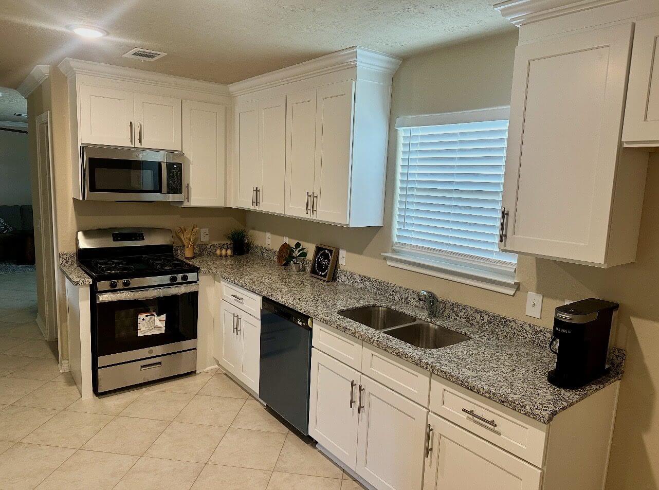 Modern kitchen with white cabinets and appliances.