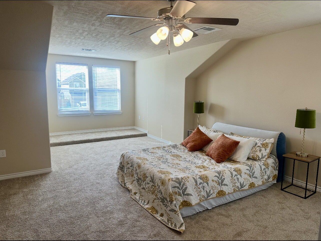 Bedroom with bed, lamps, and large window.