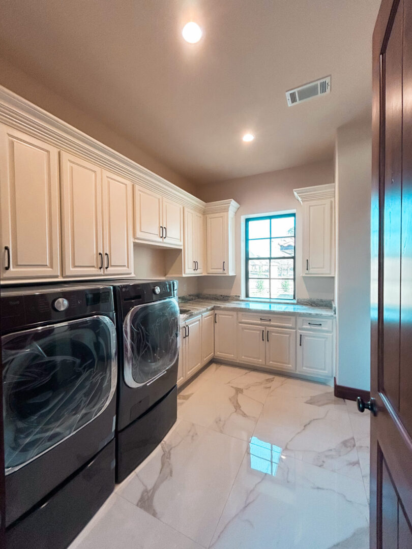 Modern laundry room with appliances and cabinets.