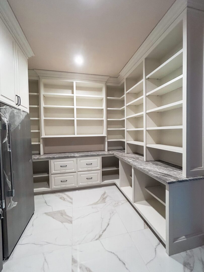 Spacious pantry with white shelves and drawers.
